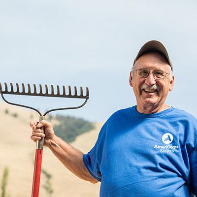 Man wearing an AmeriCorps T-shirt holding a rake