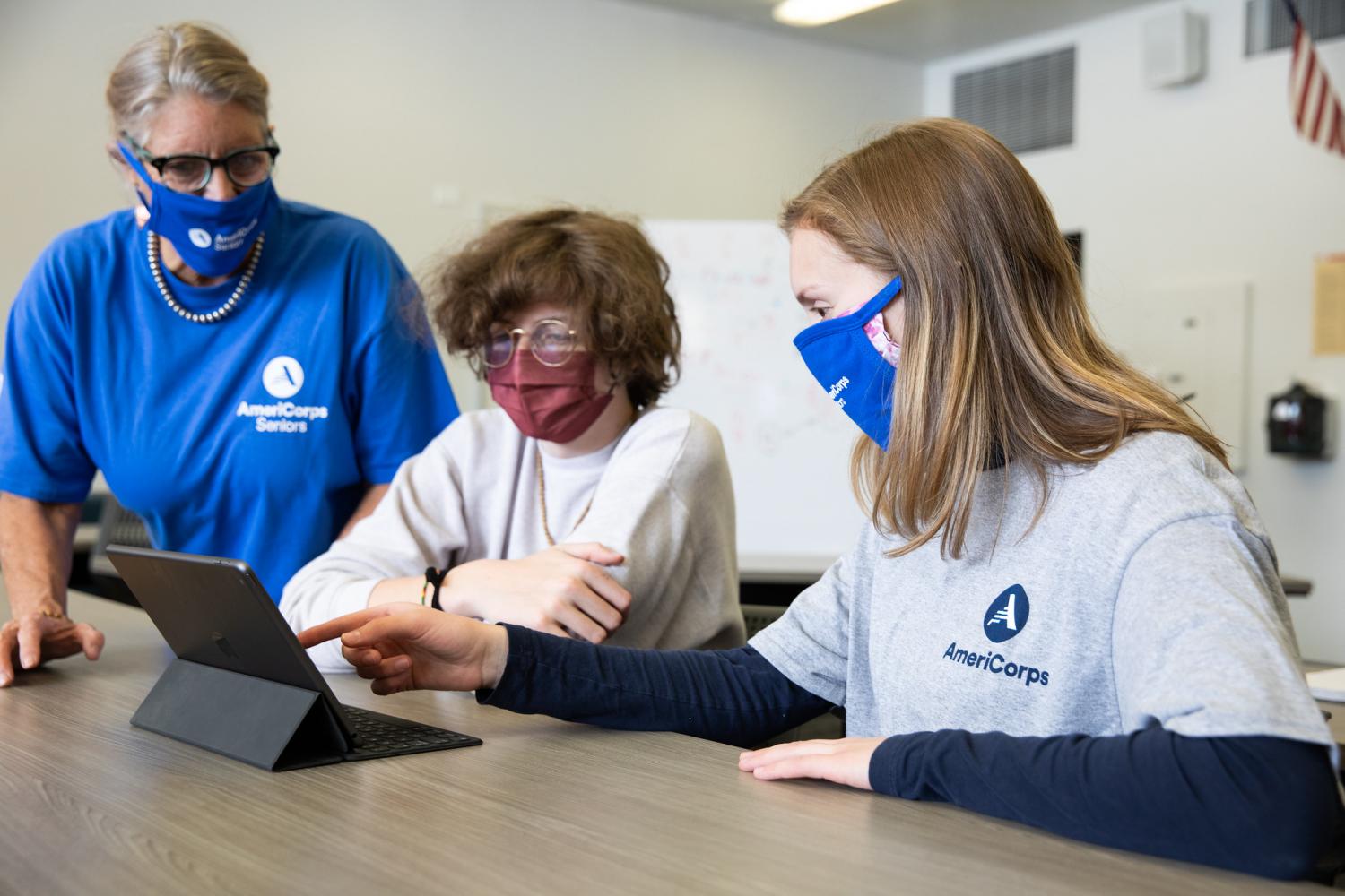 AmeriCorps members wearing masks work around a computer