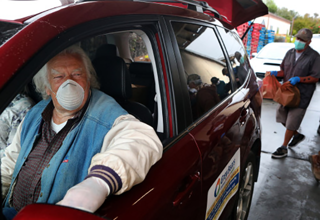 Grey Bears volunteer Charles Butler waits with his wife Alice as their car is loaded with groceries before they leave to deliver needed supplies to Santa Cruz County seniors during the COVID-19 pandemic. (Photo by Shmuel Thaler/ Santa Cruz Sentinel)