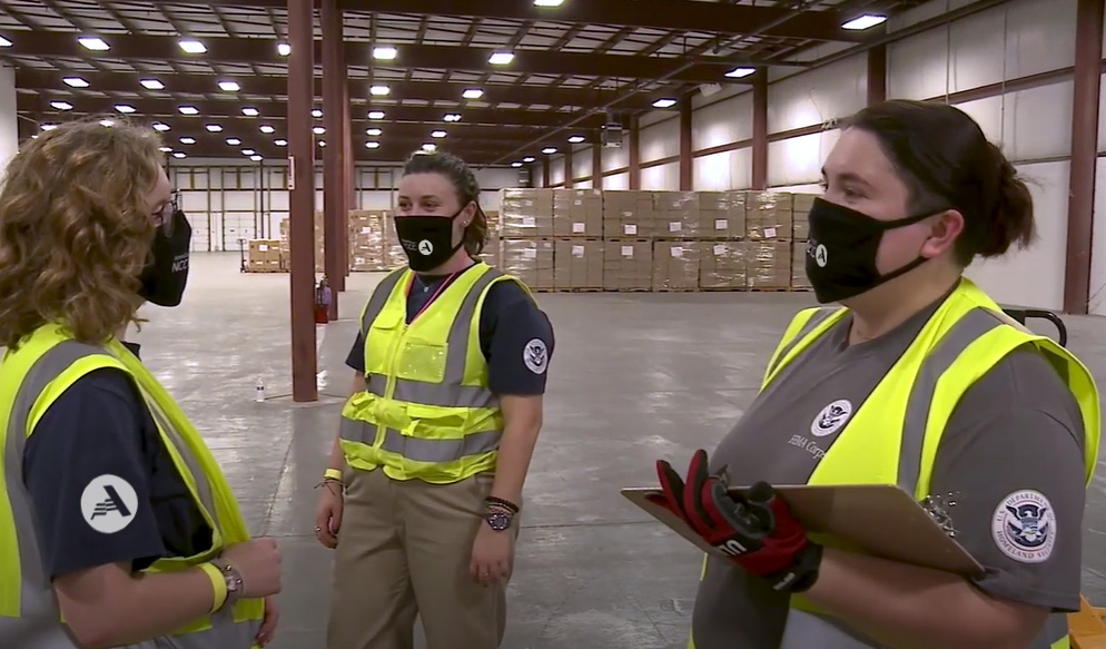 Three FEMA Corps members meeting in warehouse