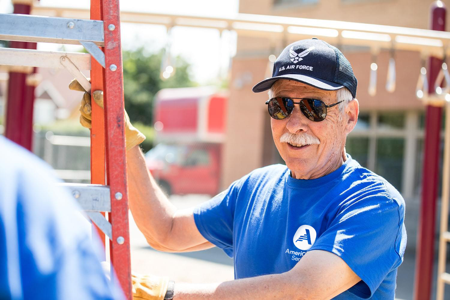 Man wearing an AmeriCorps T-shirt holding a ladder