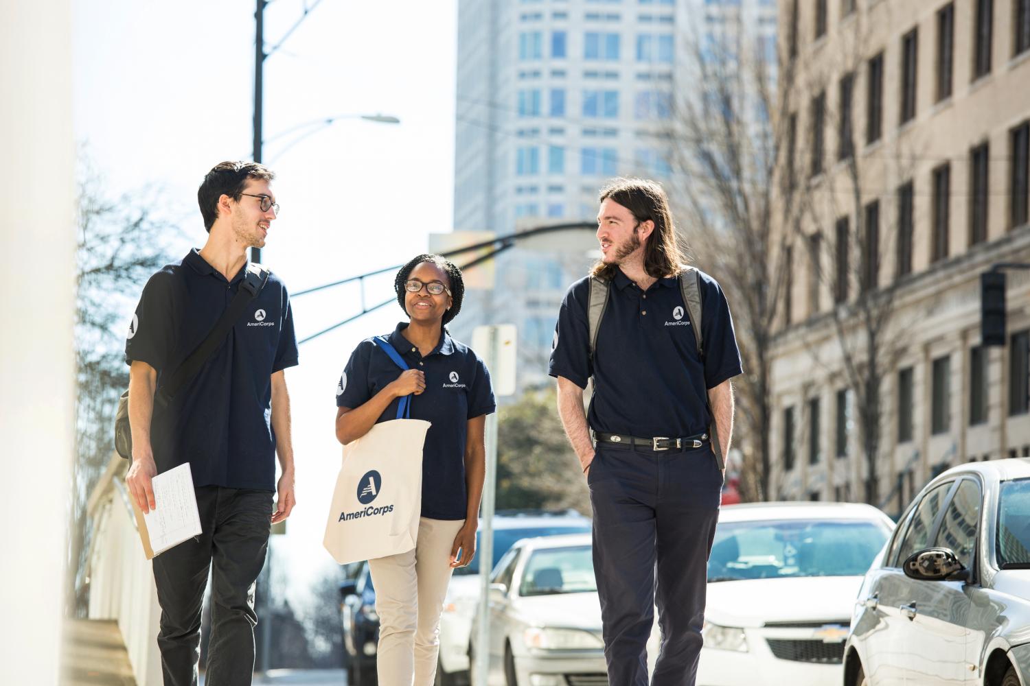 Three AmeriCorps members walking on sidewalk